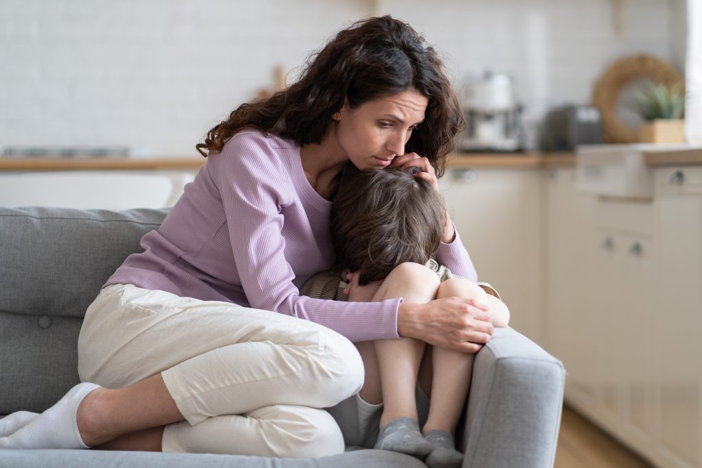 Mãe abraçando filho no sofá, pensando nos principais sintomas de epilepsia infantil