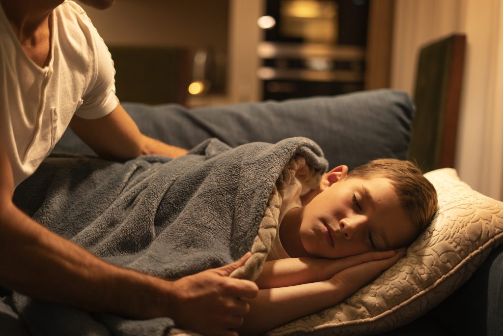 Mãe colocando o filho para dormir, preocupada com a Epilepsia noturna em crianças.