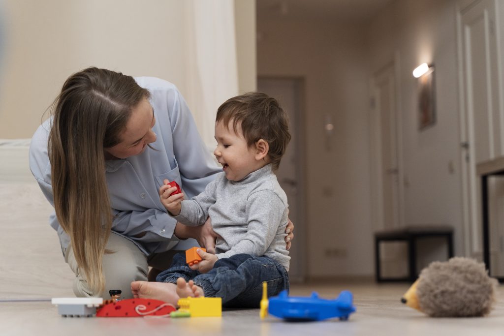 Mãe brincando no chão com criança, introduzindo o tema; Microcefalia: causas.