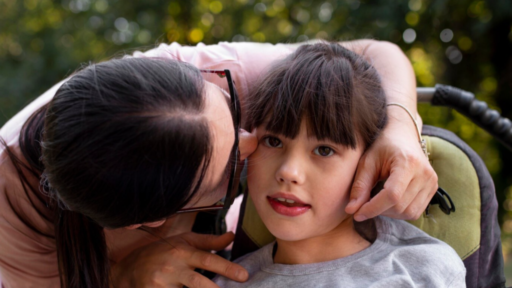 Mãe beijando a filha com paralisia cerebral, para falar sobre o dia mundial dessa condição