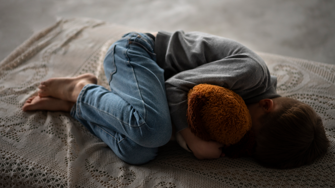 Criança deitada na cama em posição fetal, para falar sobre os sintomas pródromos de epilepsia